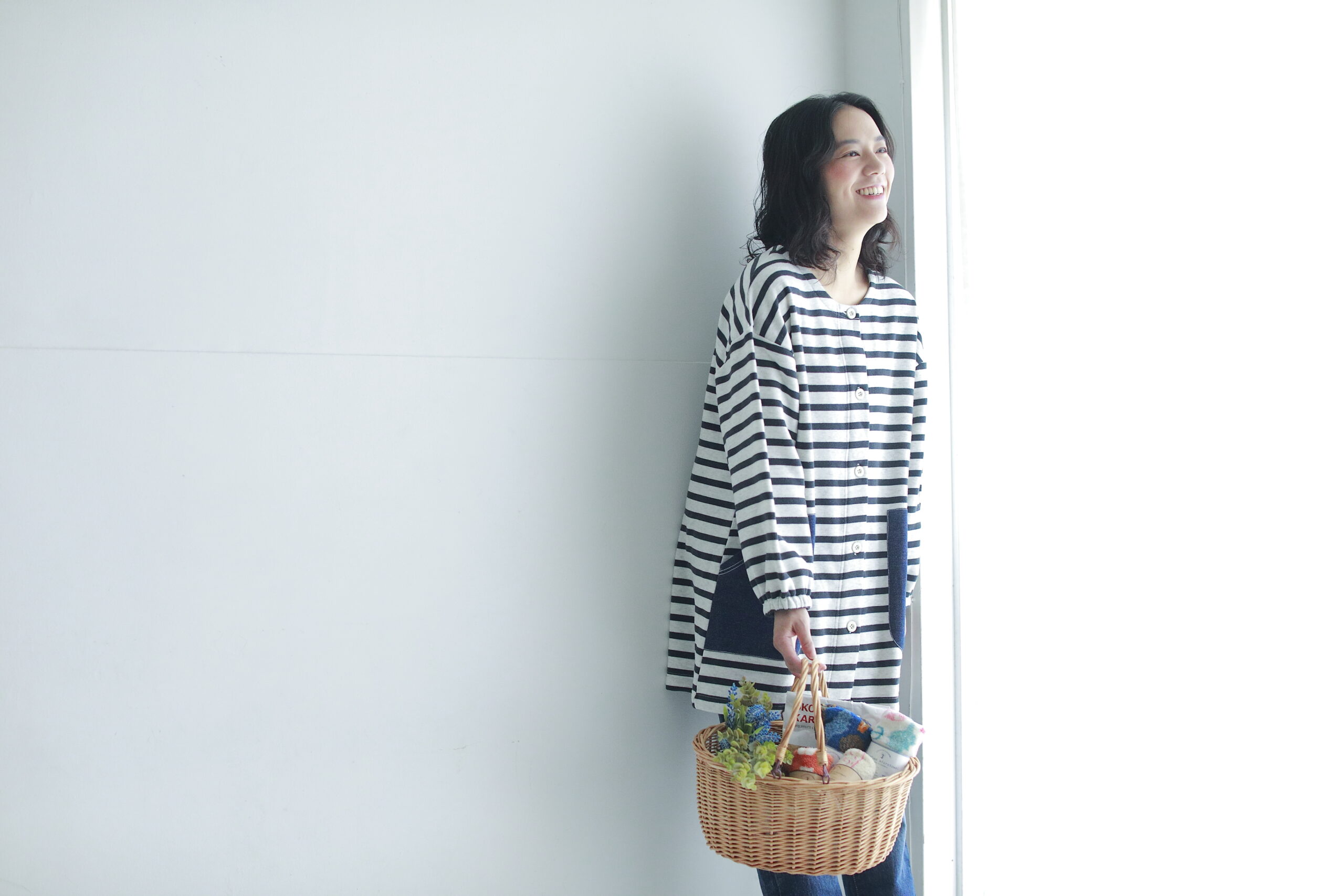 かごを持ったエプロン姿の女性モデルの写真