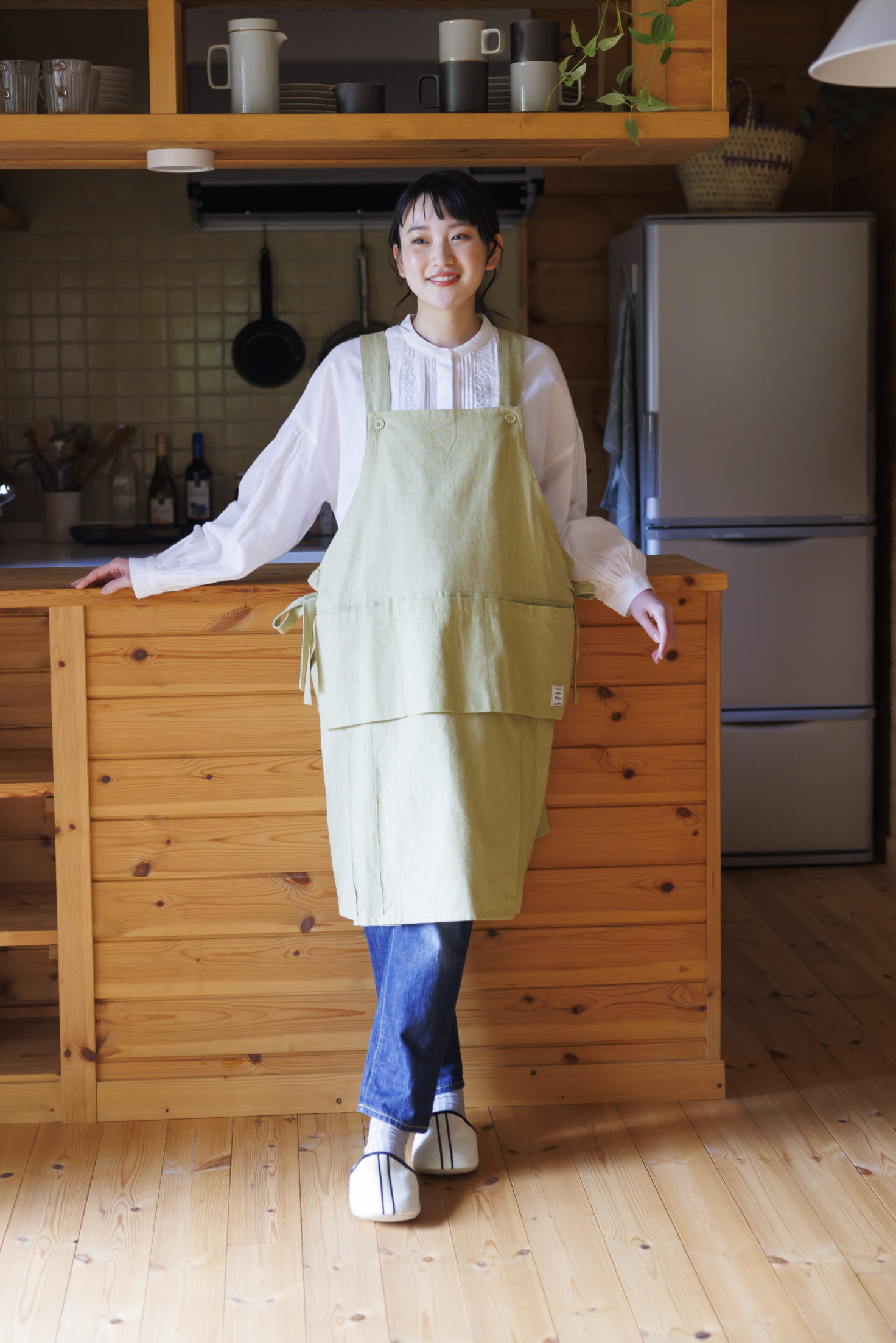 デニムパンツを履いて白いブラウスを着てエプロンを着ている女性